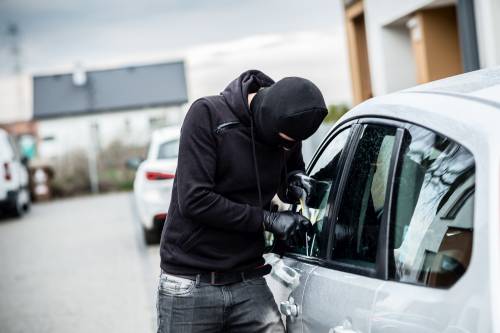 Man wearing balaclava attempting to break into a car