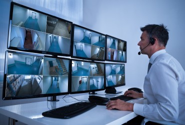 Training and Management Review Man sitting at a desk watching security camera feeds.